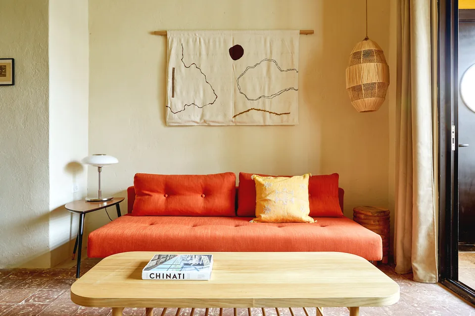 Red sofa and botanical wall hanging in APT 2