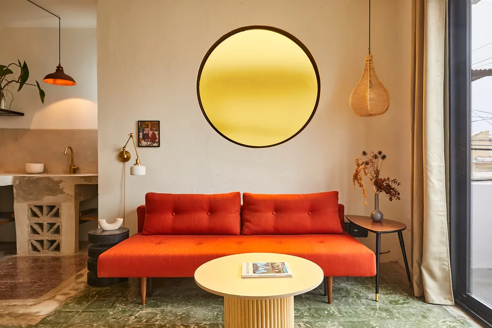 Red sofa beneath a circular amber window in APT 8