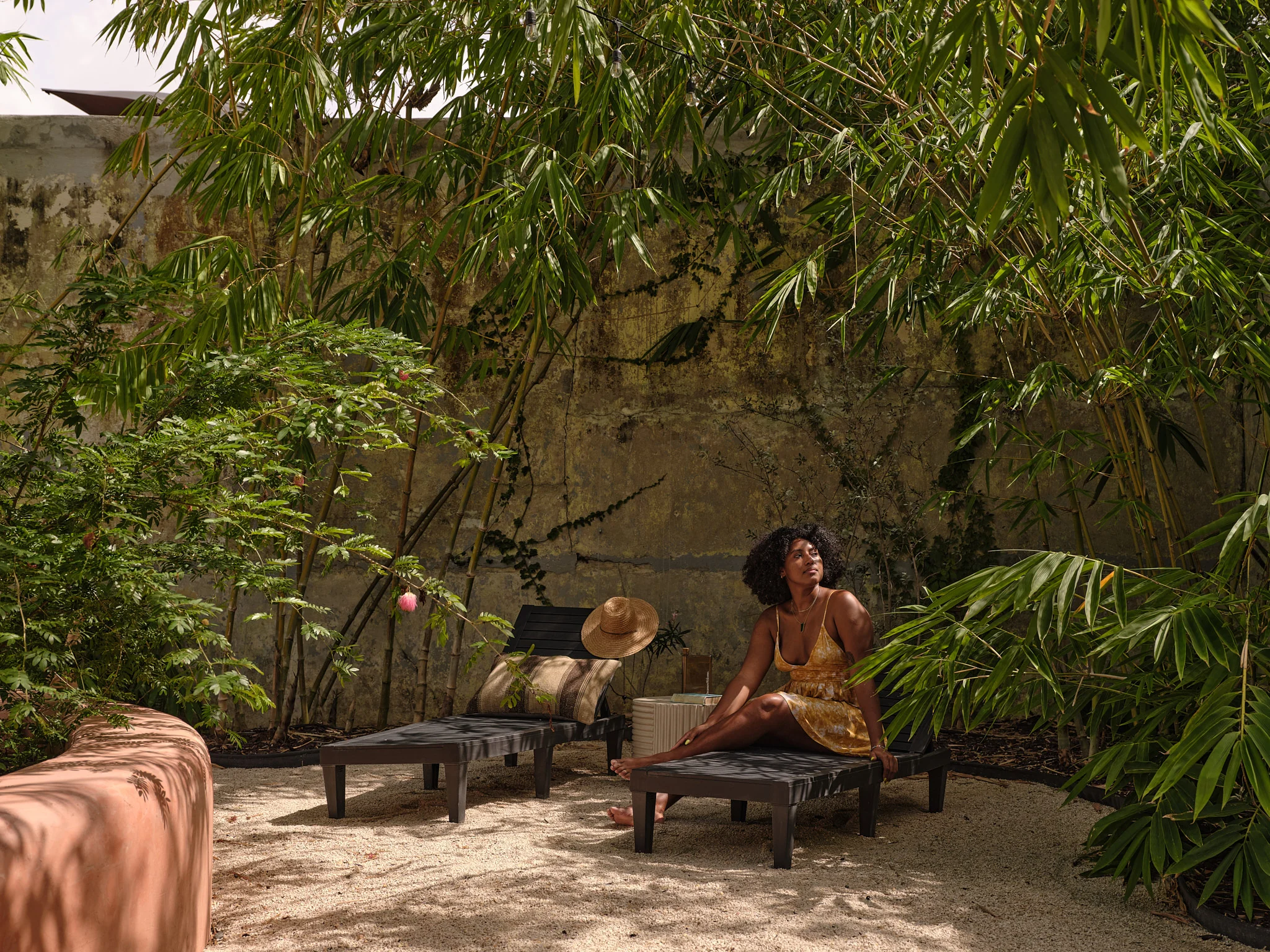A guest resting beneath bamboo in Casa Frida’s warm, textured garden.
