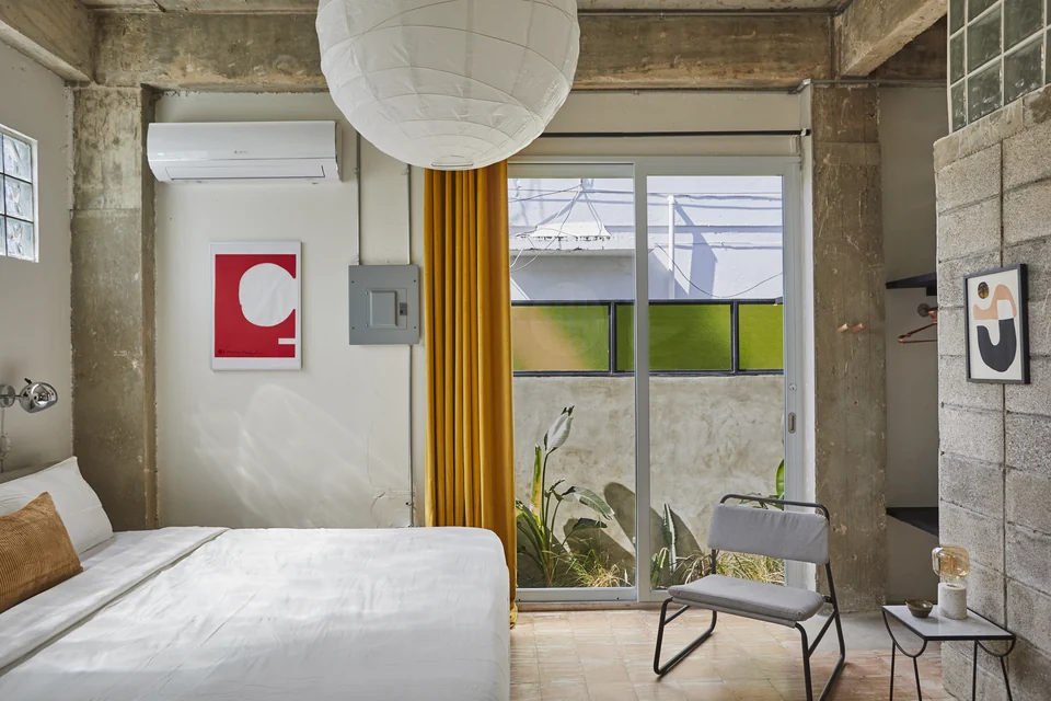 DA1’s king bed and tall industrial-style windows with colored glass