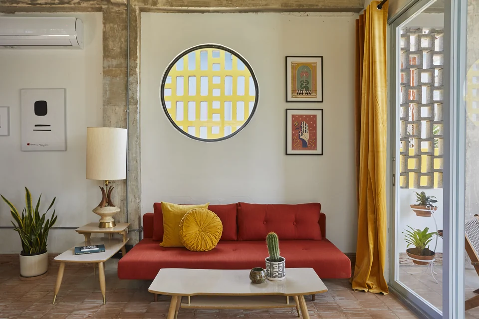A red sofa bed and yellow circular window in DA1’s living area