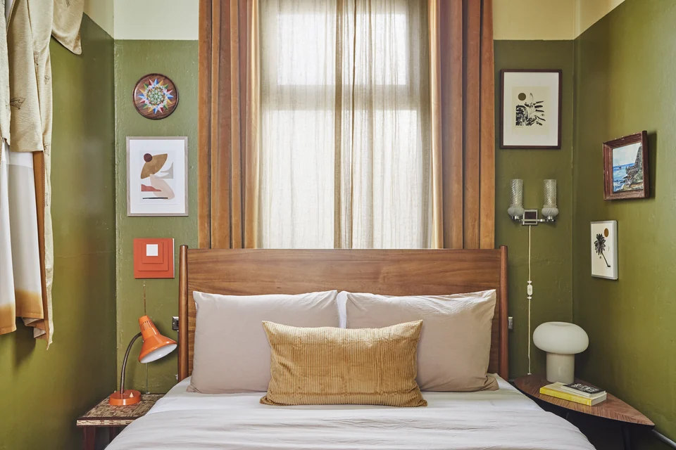 A queen bed, olive-green walls and framed artwork in DA2’s separate bedroom