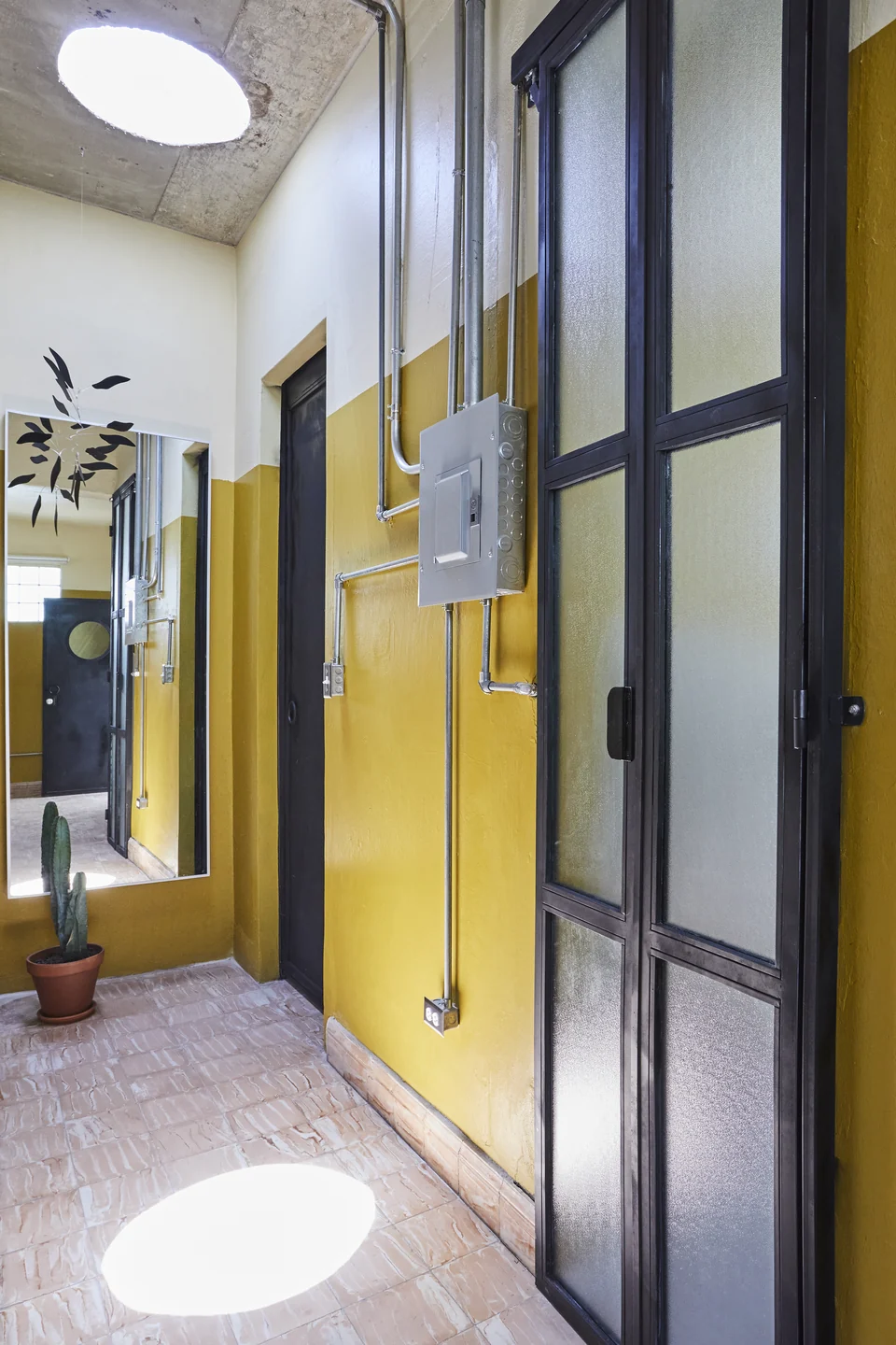 A black-paned door, circular skylight and yellow walls inside DA2