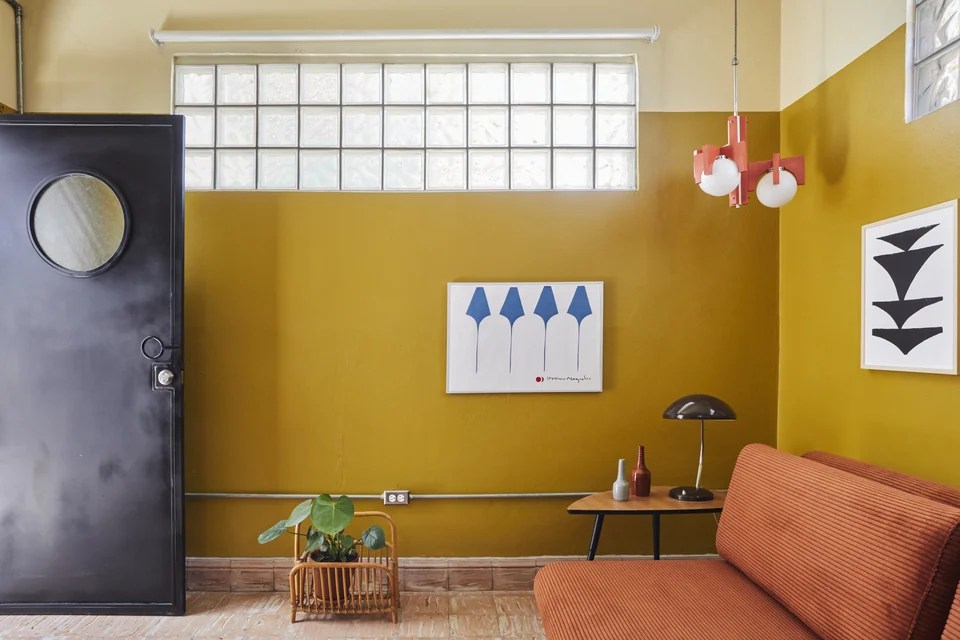 Mustard walls, a terracotta sofa bed and artwork in DA2’s living room