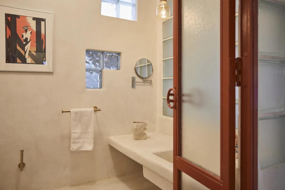 Concrete walls, framed artwork and a vanity in JA1’s bathroom