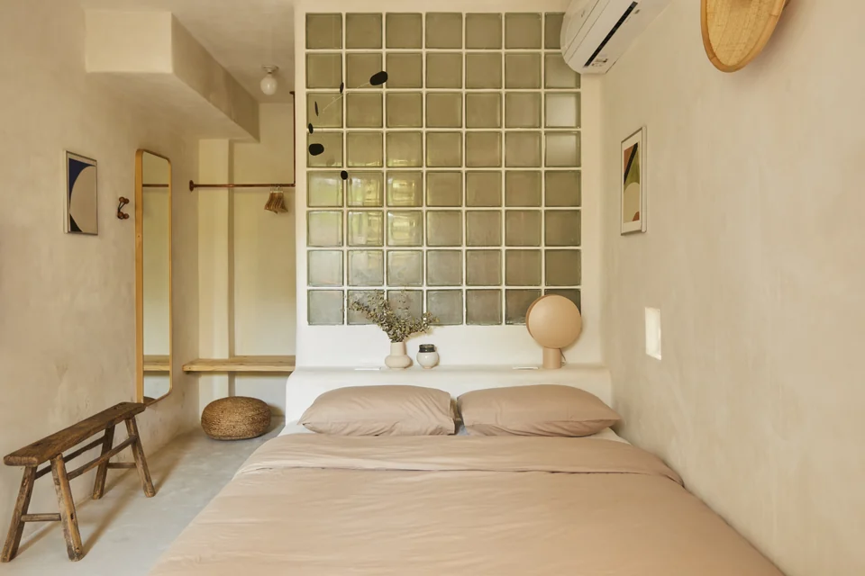 JA1’s queen bed, glass-block partition and soft neutral studio interior