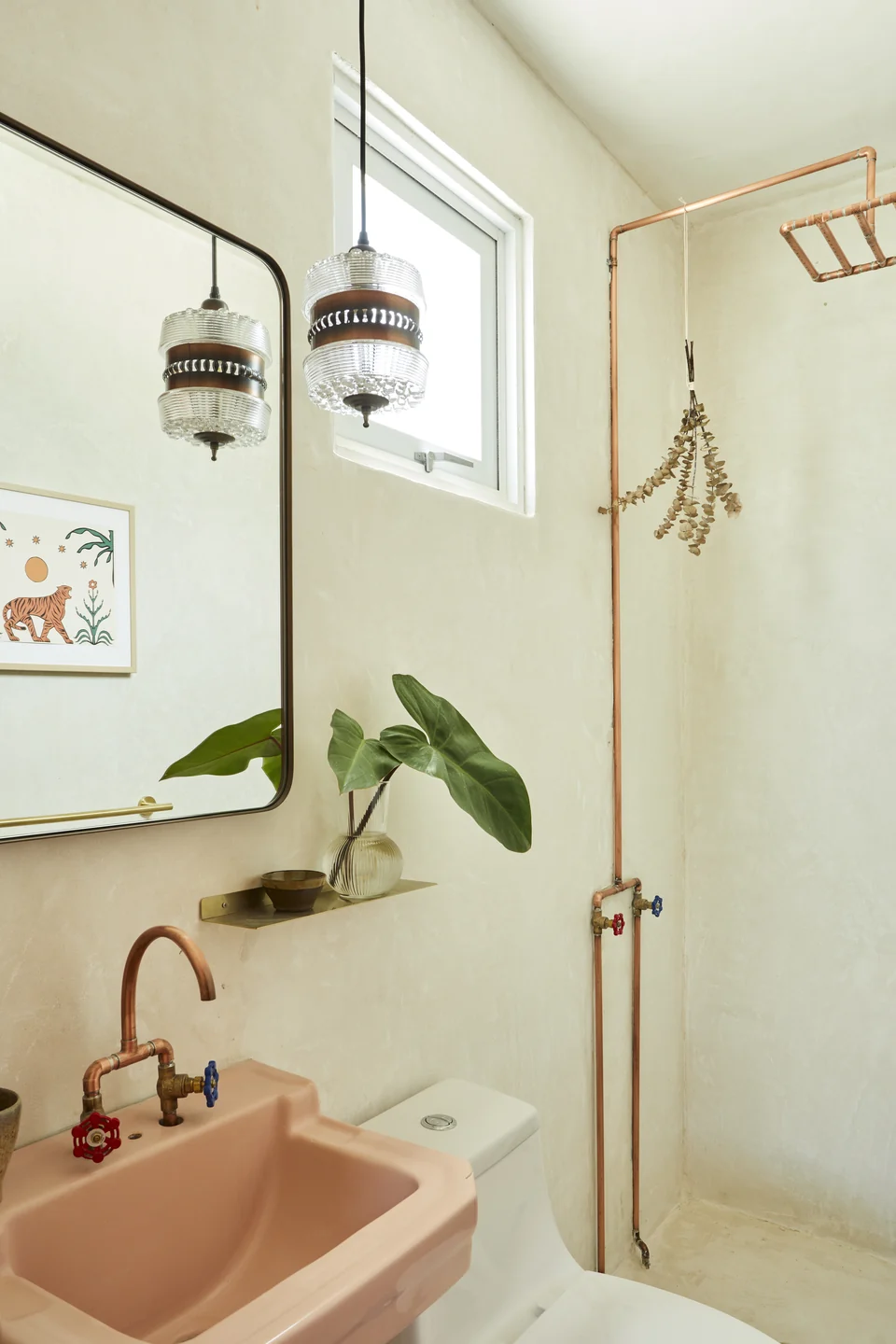 A blush basin and brass shower fittings in JA2’s bathroom