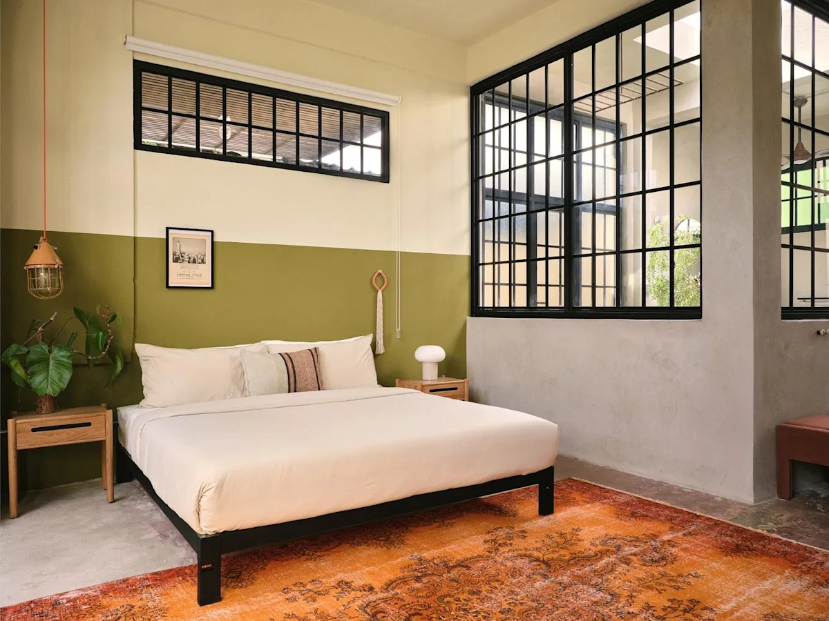 A loft studio bedroom at Paz by DW, a Dreamers Welcome stay in San Juan, with olive-green walls and tall industrial windows.