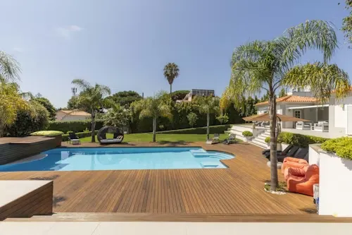 image of pool with palm trees and a villa to the right.