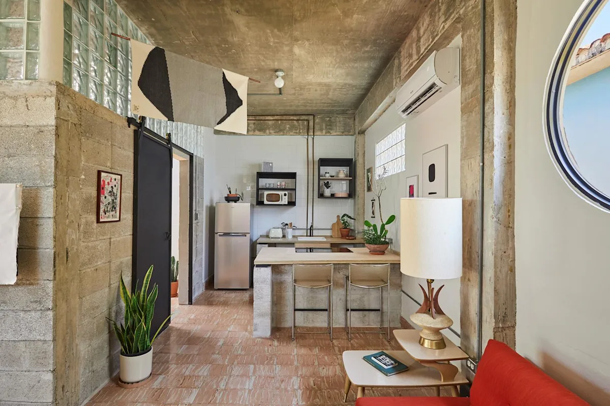 The loft living area and kitchen of an apartment at DaDa JaJa by DW in Santurce, with a red sofa and polished concrete walls.