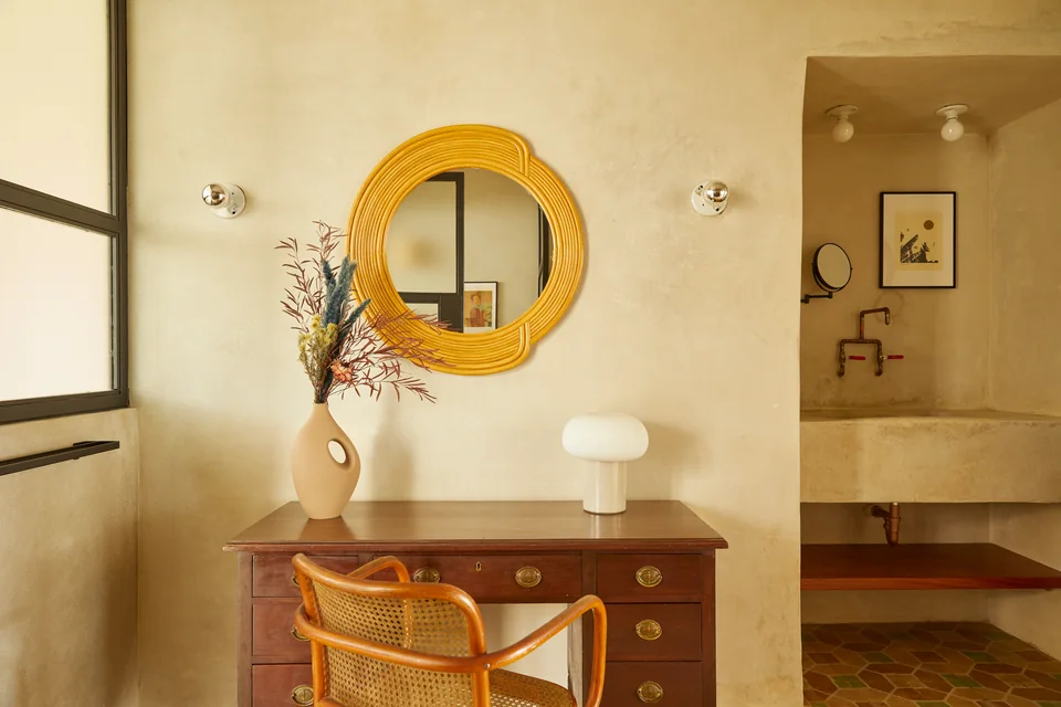 Golden circular mirror and wooden vanity in Dreamer’s bathroom