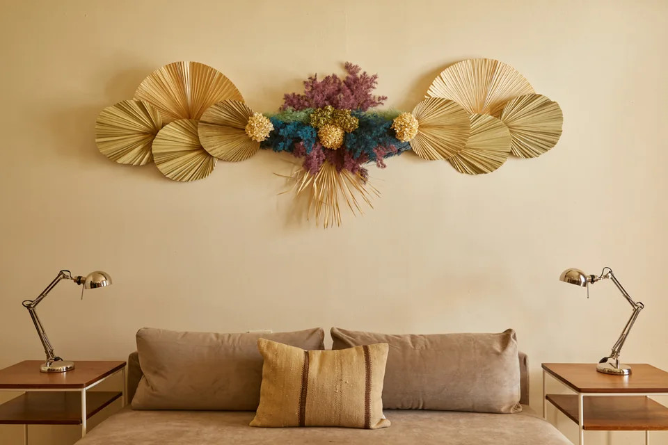 Dried palms and colorful florals by Marcos Toledo above Dreamer’s sofa