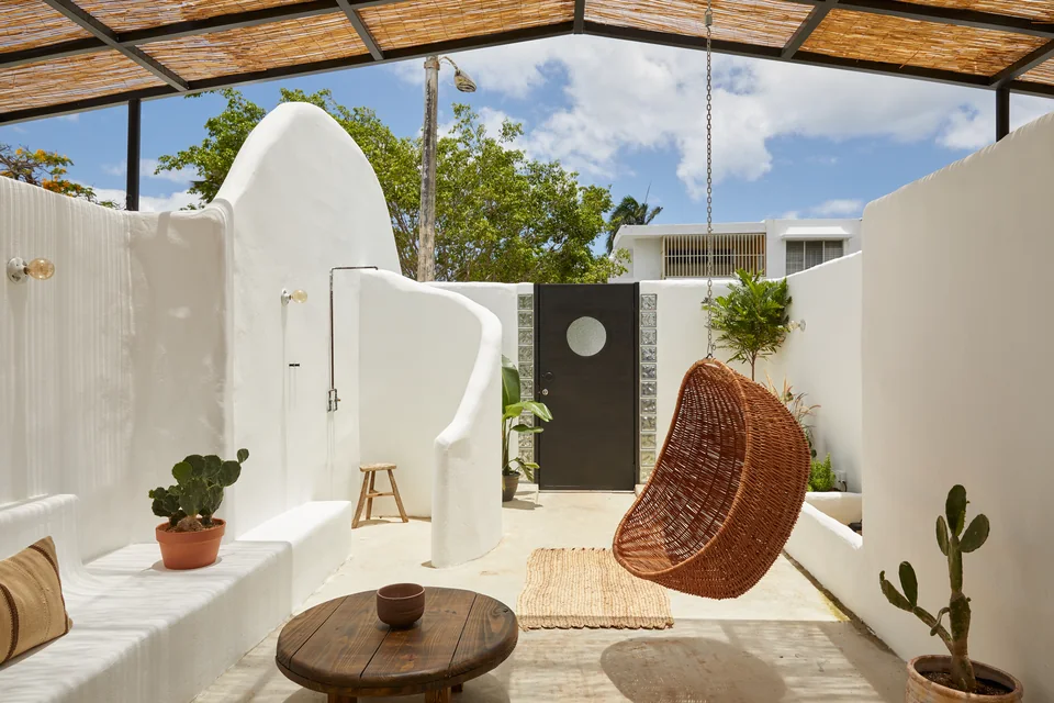 A woven hanging chair, outdoor shower and white walls on Dreamer’s terrace