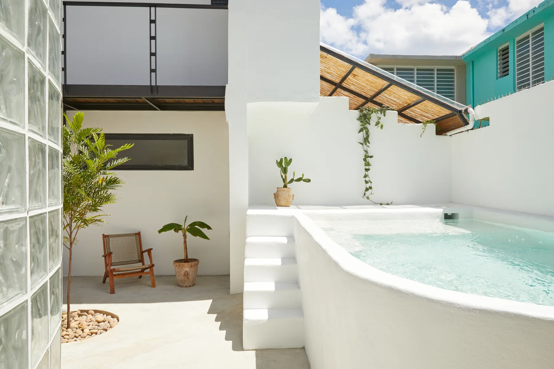 Shared saltwater pool beside Duna’s white courtyard walls and turquoise shutters