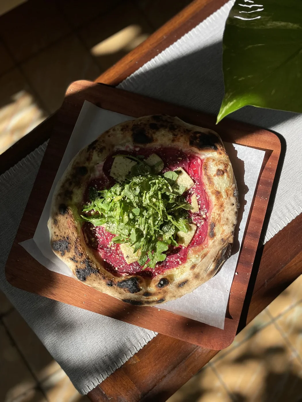 A plant-based dish on a wooden serving board in dappled light.