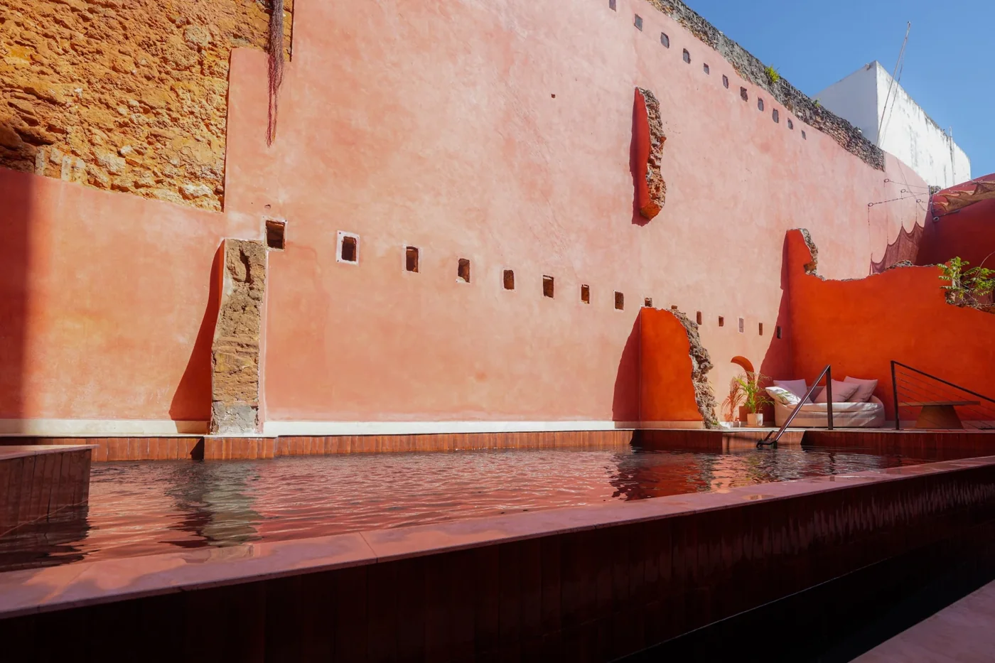 Terracotta and pink mineral walls beside a plunge pool at Las Ruinas.
