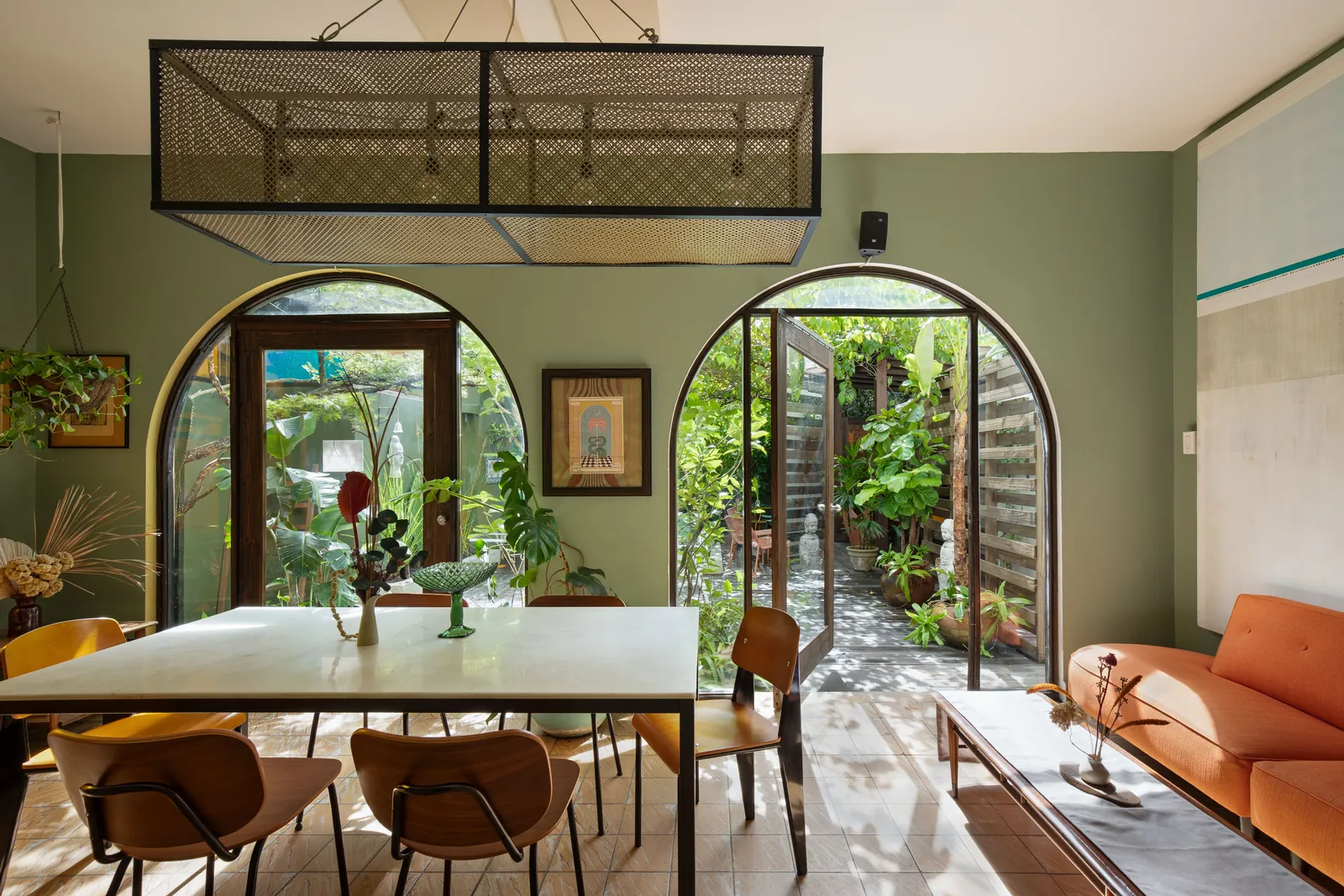 A green-walled Dreamcatcher dining room with a communal table and circular garden openings.