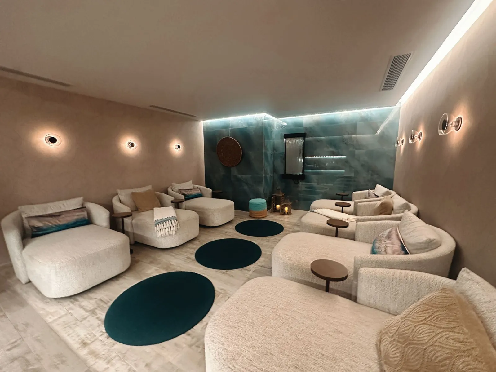 Curved pale seating and dark blue circular rugs in a softly lit San Juan spa lounge.