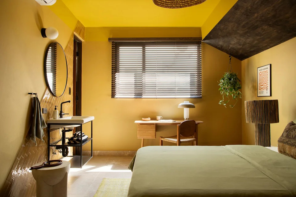Ochre walls, a bed and a desk in a Maru guestroom