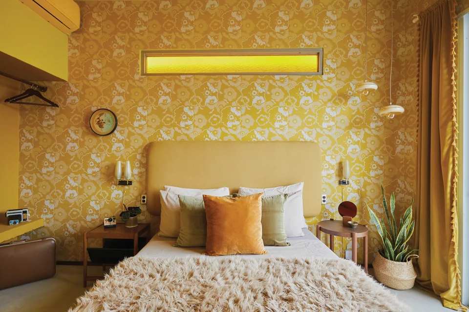 Warm yellow floral wallpaper and a bed in Diana’s first bedroom
