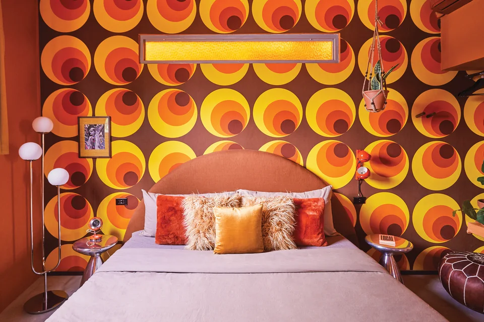 Retro orange and red wallpaper behind the bed in Diana’s second bedroom