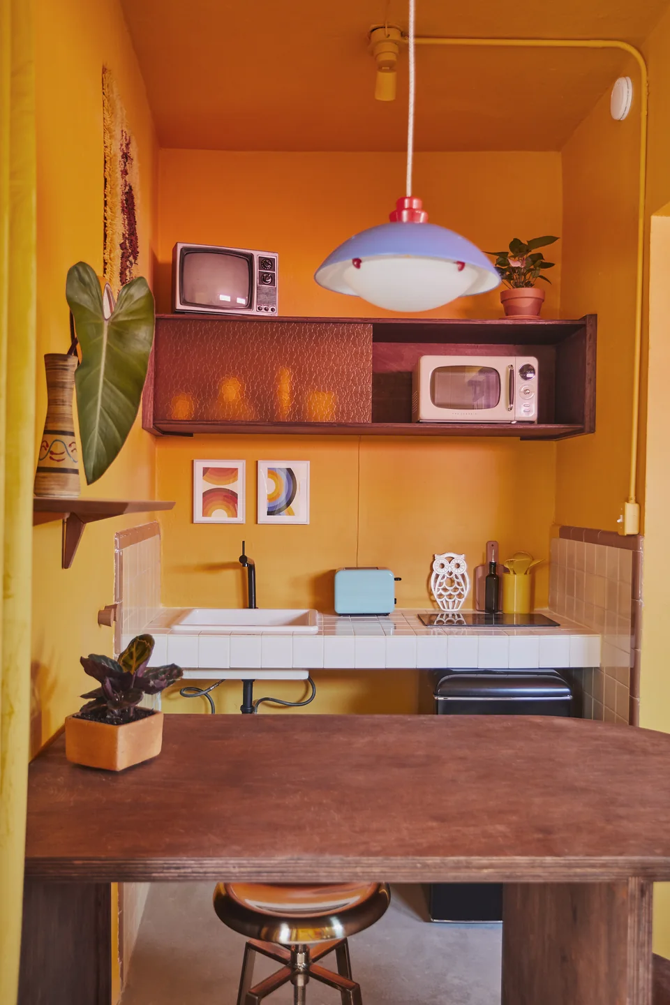 Orange and yellow cabinetry, a microwave and small fridge in Donna’s kitchenette