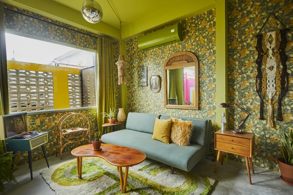 Pea-green walls, floral wallpaper and a teal sofa in Gloria’s living room