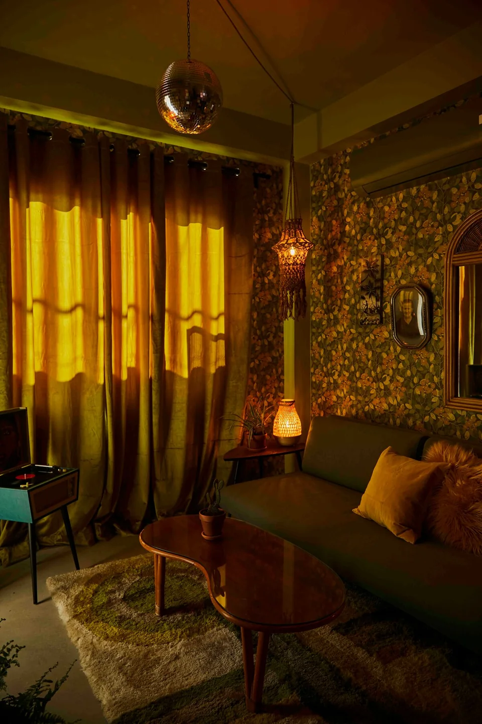 Gloria’s green living room with a mirrored disco ball and warm low lighting