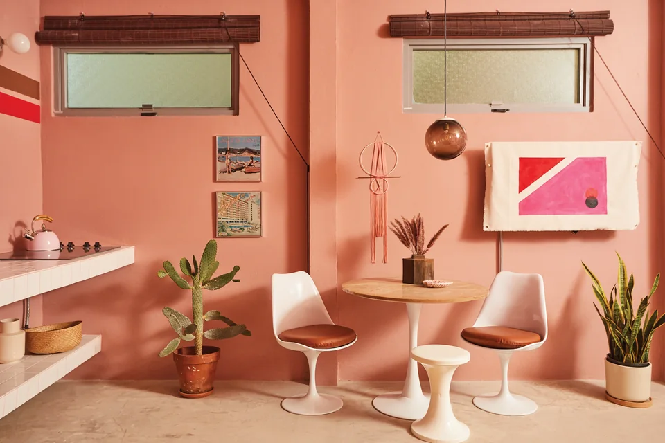 Pink walls, framed prints and tulip chairs in Grace’s dining corner