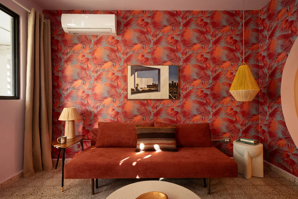 Red patterned wallpaper and curved seating in A’s living area