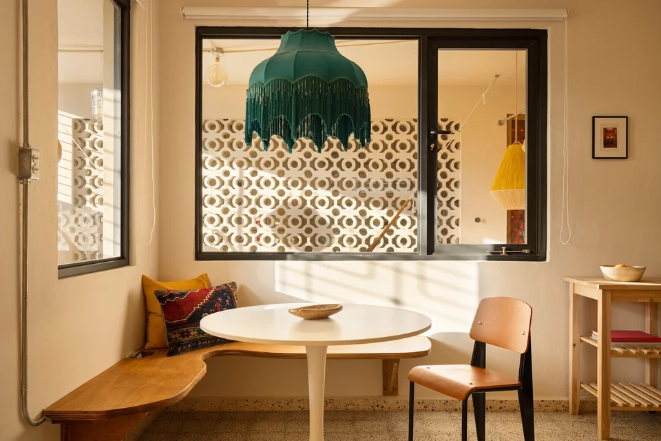 A round dining table and green pendant beside N’s kitchen