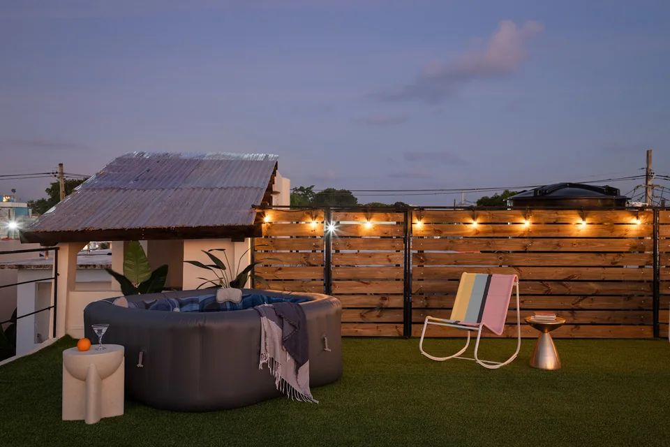 String lights and a hot tub on O’s private roof deck at dusk