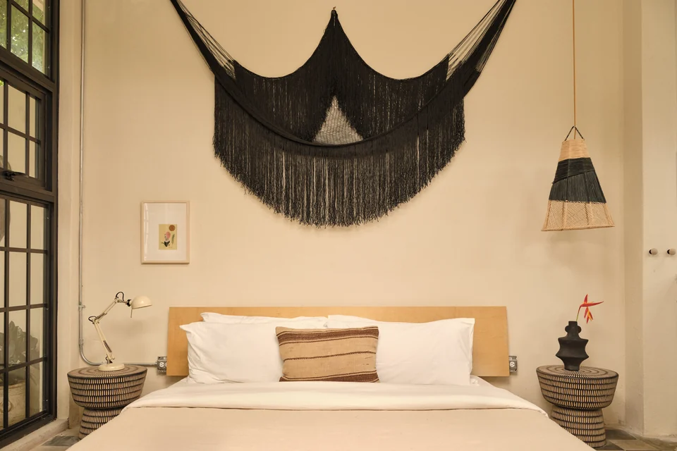 A king bed, black textile artwork and warm lamps in Paz 1