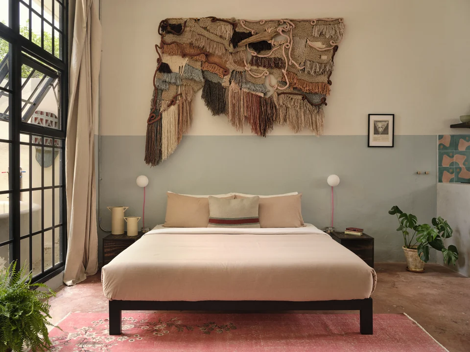 Paz 2’s king bed, textile wall hanging and soft green walls