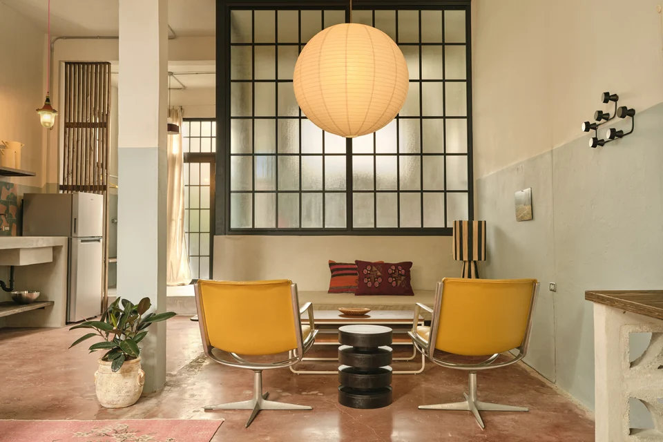 Two yellow armchairs and a paper lantern in Paz 2’s light-filled seating area