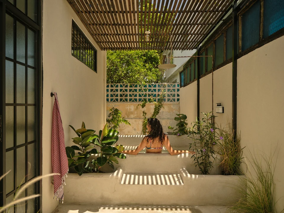 A guest in Paz 3’s private concrete soaking tub beneath the slatted patio shade