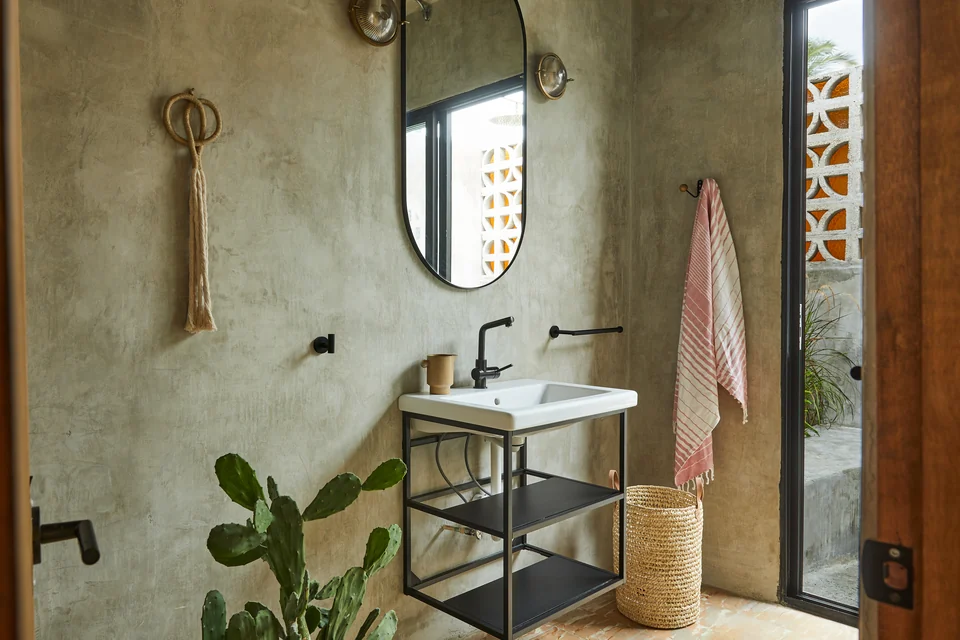 Polished concrete walls, a round mirror and vanity in Rosa 1’s bathroom