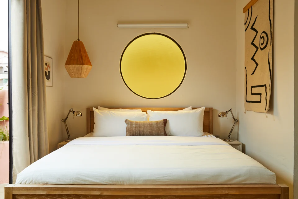 A king bed, woven pendant and yellow round mirror in Rosa 1