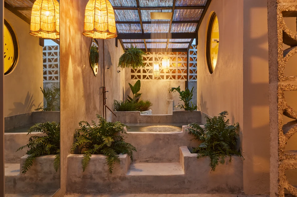 Warm pendant light over Rosa 2’s outdoor soaking tub and tropical plants