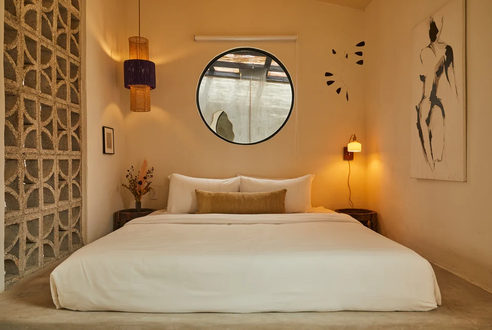 A king bed, circular mirror and decorative breeze-block partition in Rosa 2