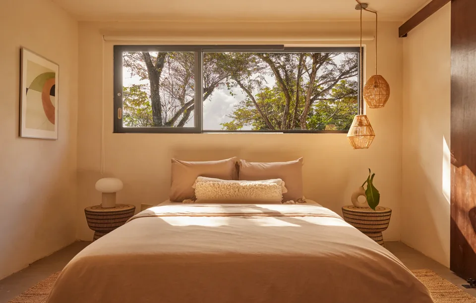 Selva’s third bedroom framed by a wide window looking into the trees