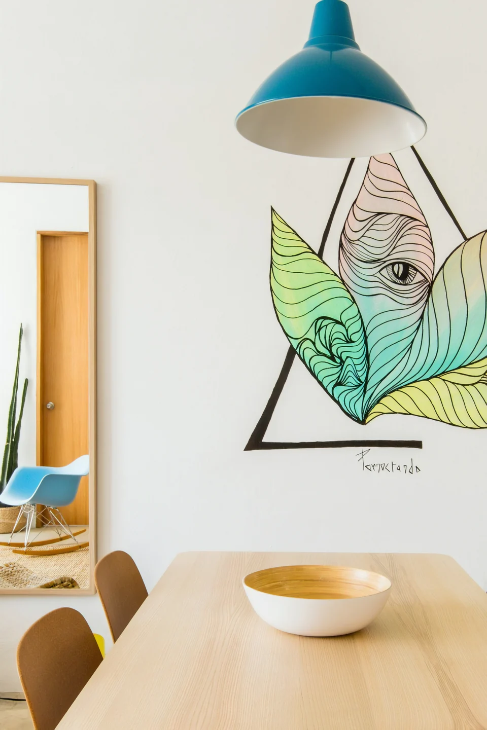 A blue pendant light and graphic bird artwork beside Adventurer’s dining table