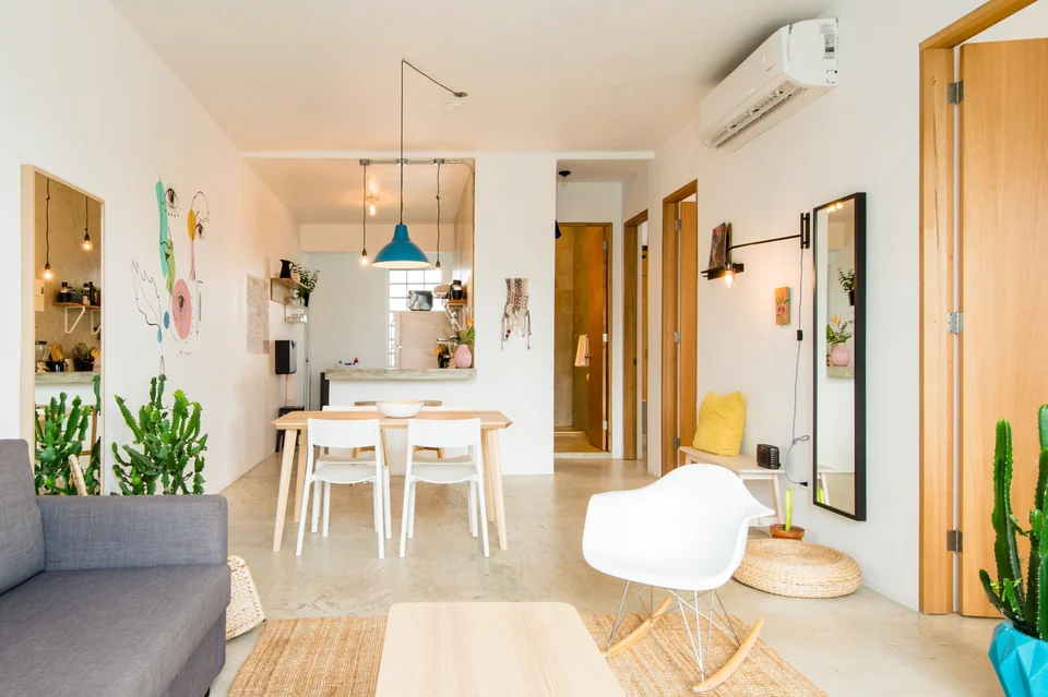 Dreamer’s sunlit living and dining rooms with pale walls and tropical artwork