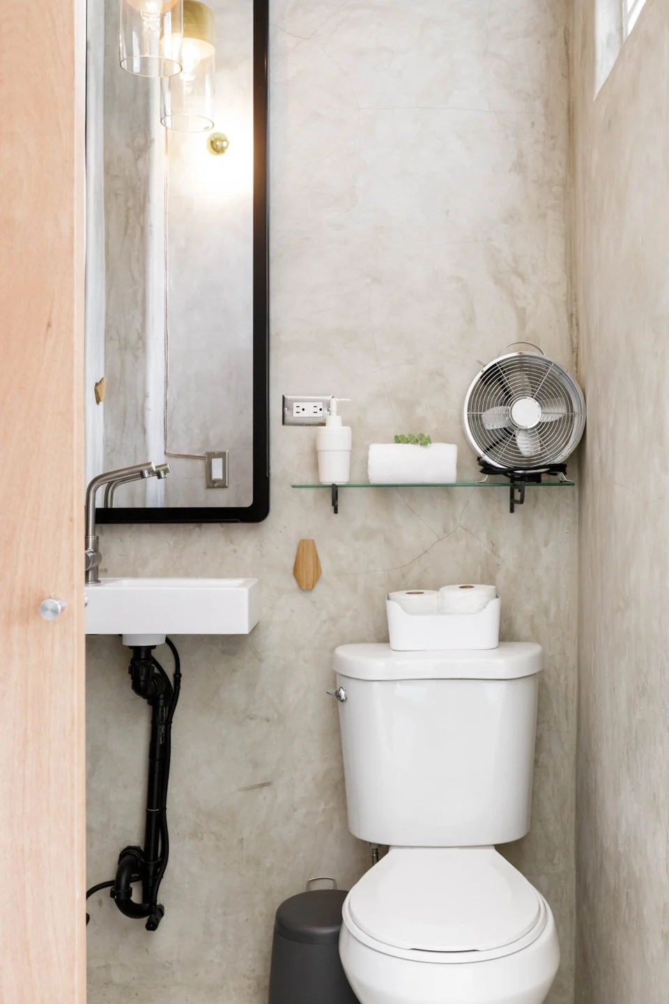 Lover’s compact bathroom with a mirror, basin and concrete walls