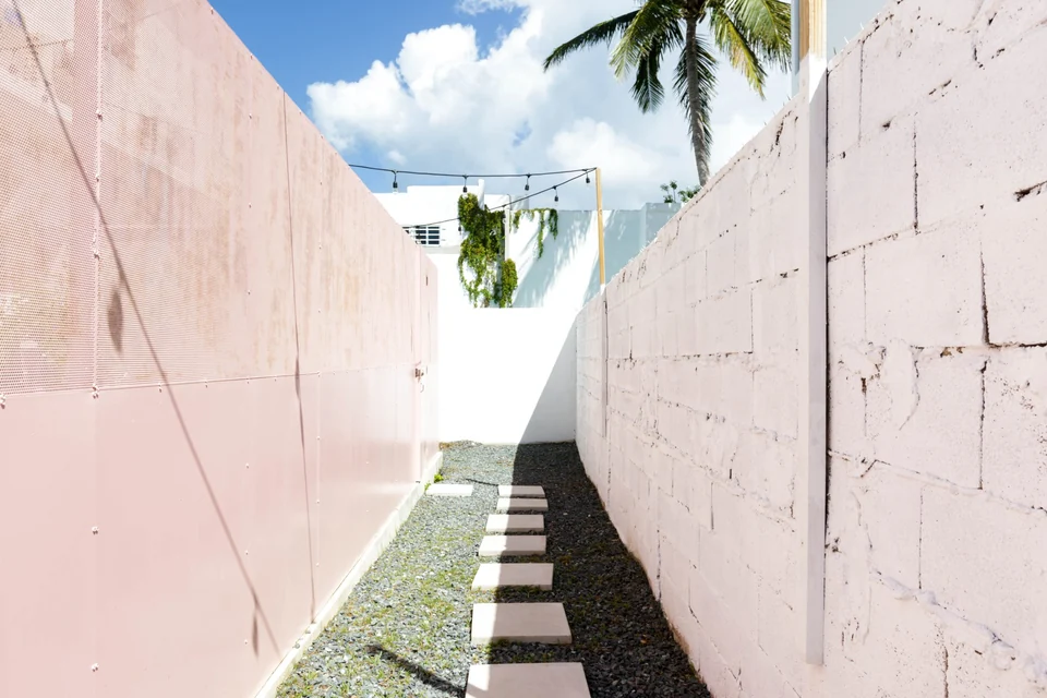 A narrow sunlit passage between pink walls beside Lover’s terrace