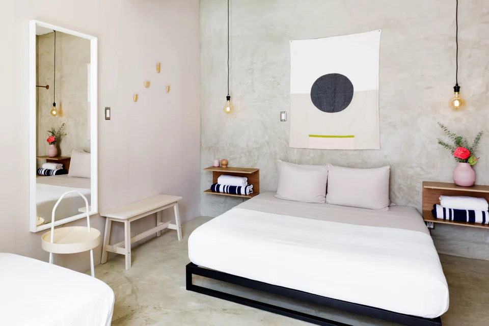Lover’s queen bed, woven pendants and pale concrete studio interior