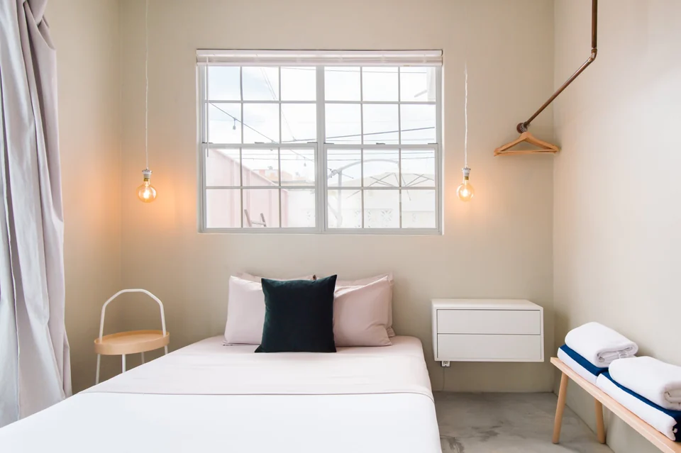 Nomad’s first queen bedroom with a pale wall and soft pendant light
