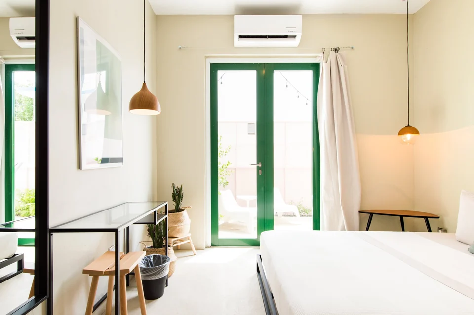 A queen bed and green-framed terrace doors in Nomad’s second bedroom