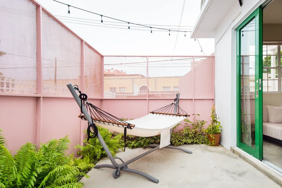A hammock beneath a slatted roof between Nomad’s pink courtyard walls