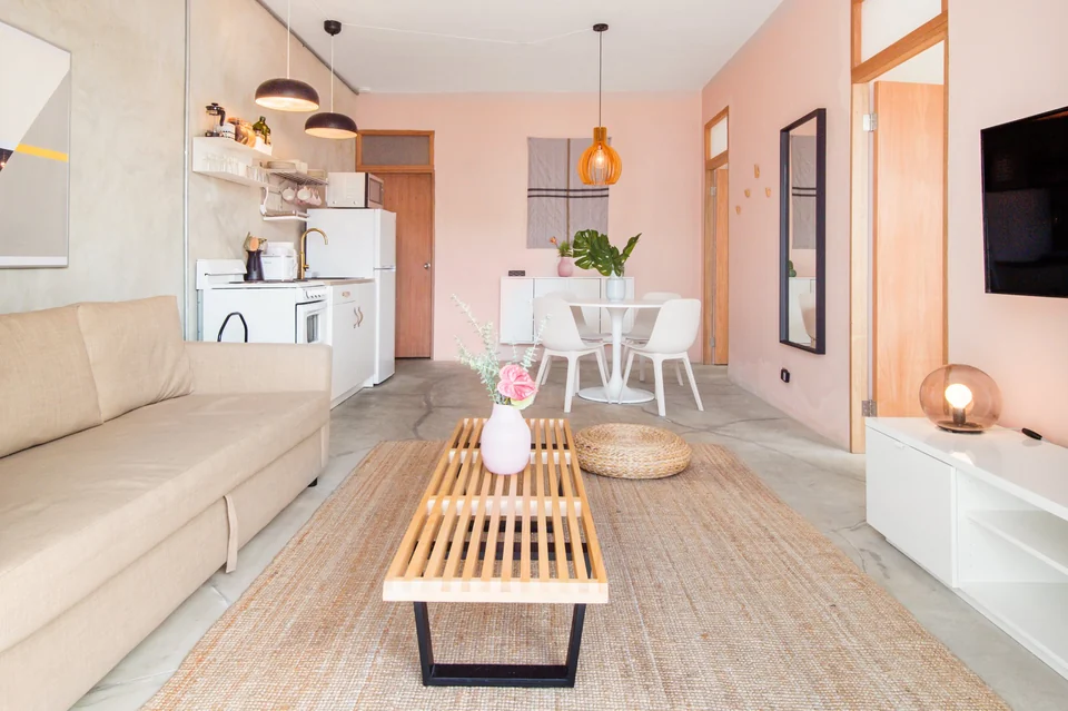 Nomad’s pale-pink living and dining room with a white sofa and rattan lights